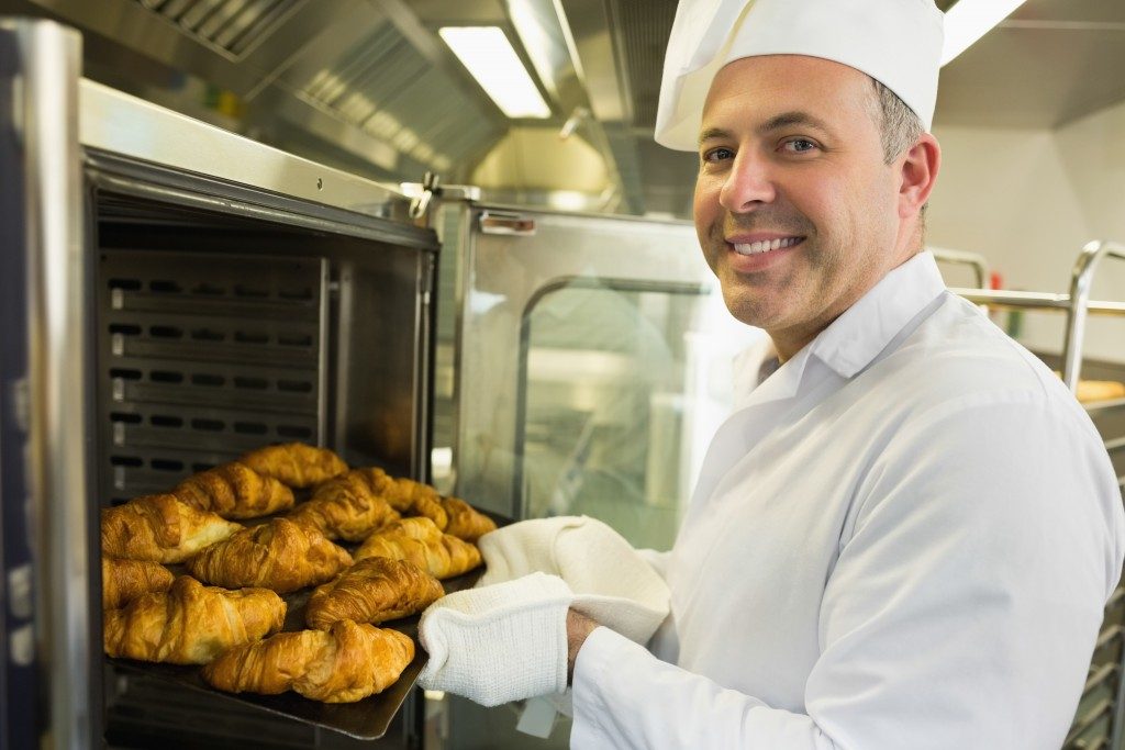 chef taking out the baked croissants from the oven
